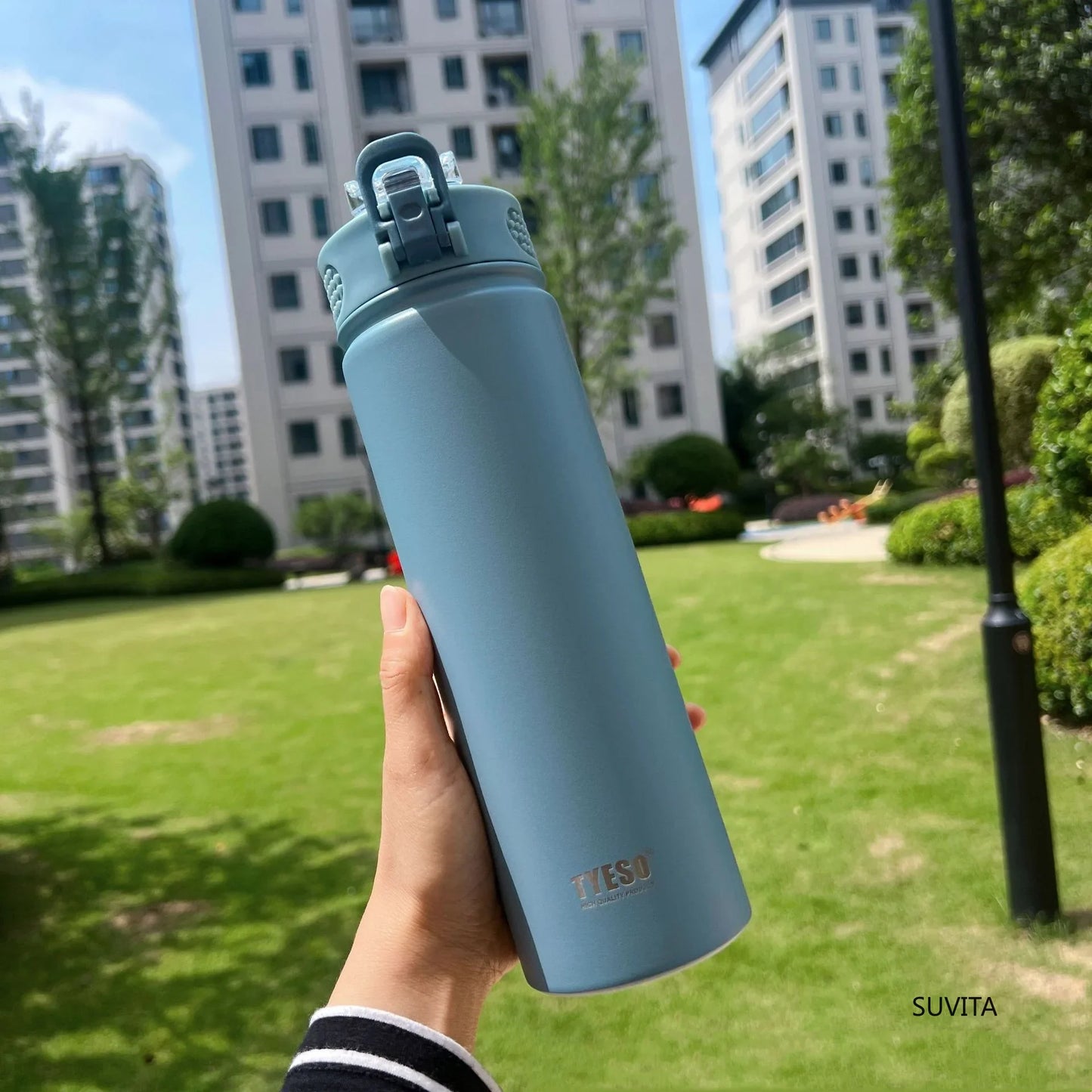 TYESO blue thermos bottle with straw held outdoors. Leak-proof and BPA-free, perfect for hydration on the go.