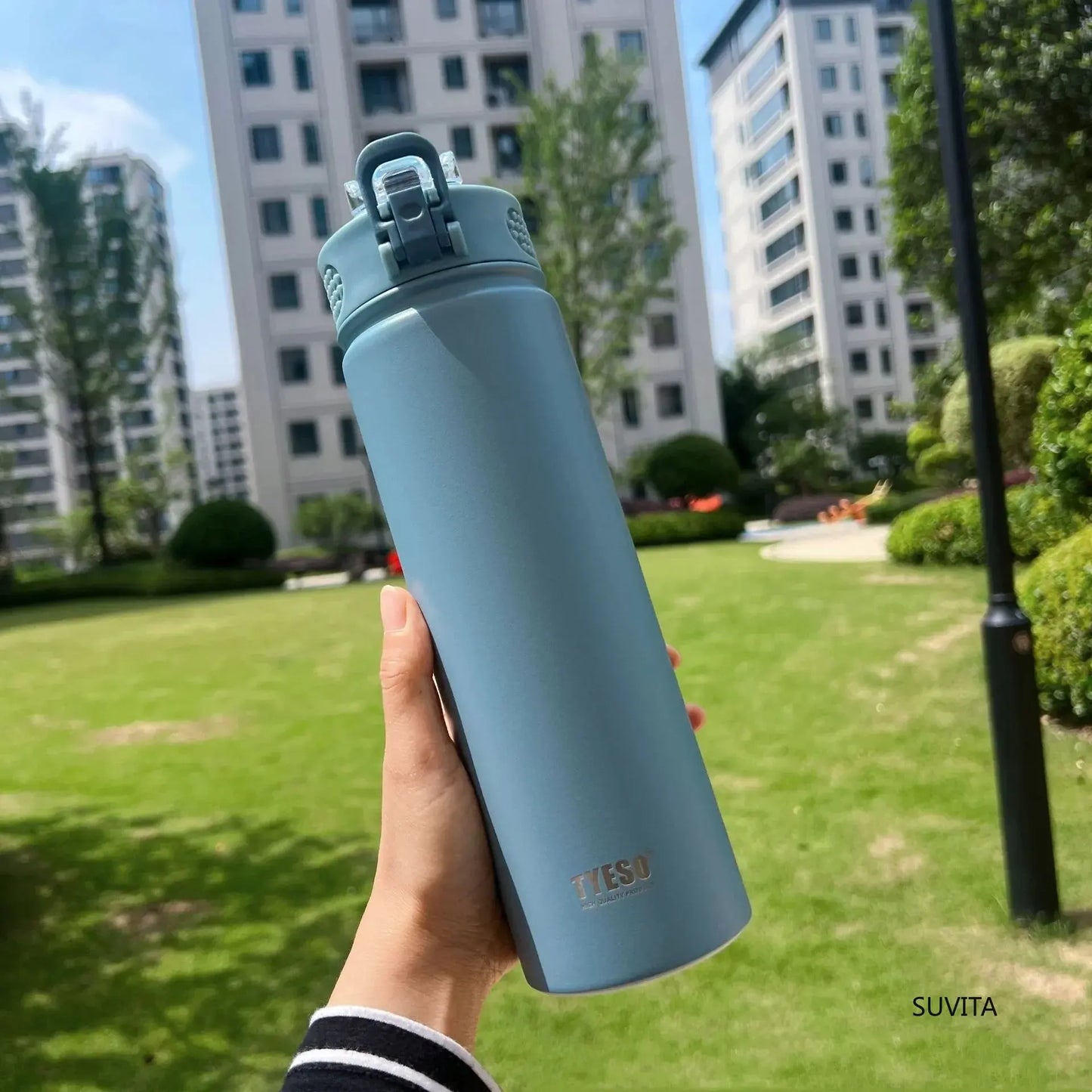 TYESO blue thermos bottle with straw held outdoors. Leak-proof and BPA-free, perfect for hydration on the go.