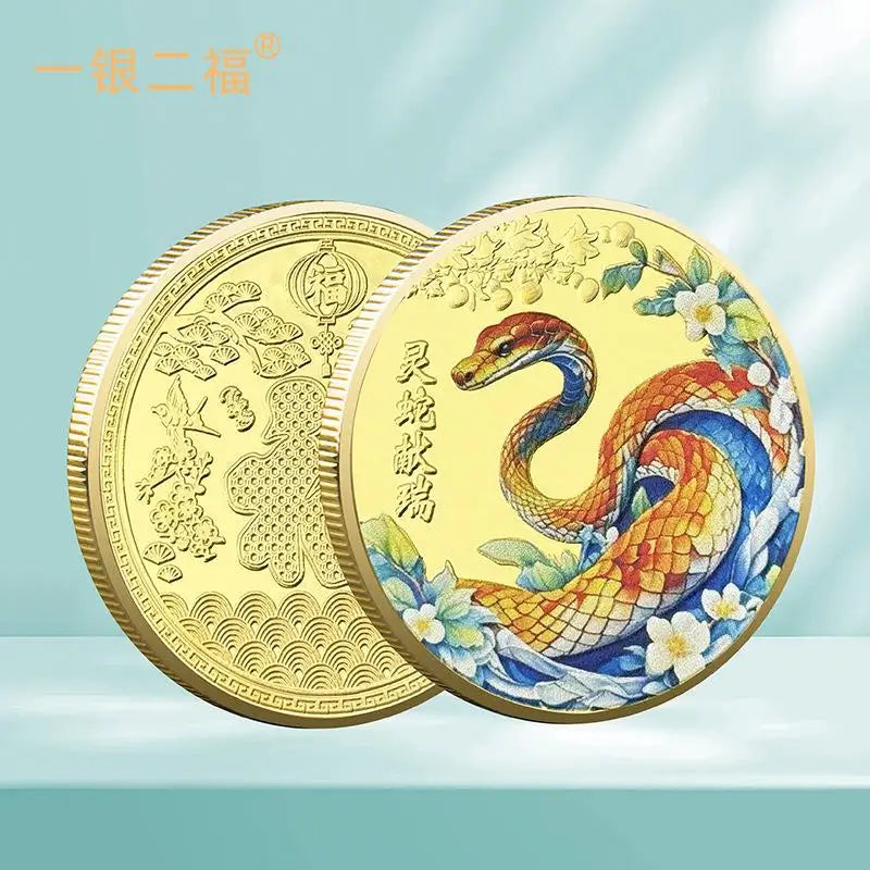 A collectible coin with a 3D relief design of a snake and floral patterns, predominantly in gold and silver colors.