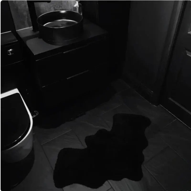 Dark bathroom with a sink and toilet, featuring a large black shadow on the floor.
