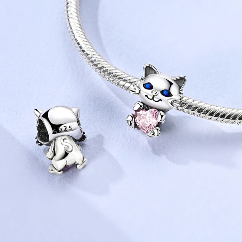 Silver cat-shaped charm with a pink heart on a light blue background. pandora style