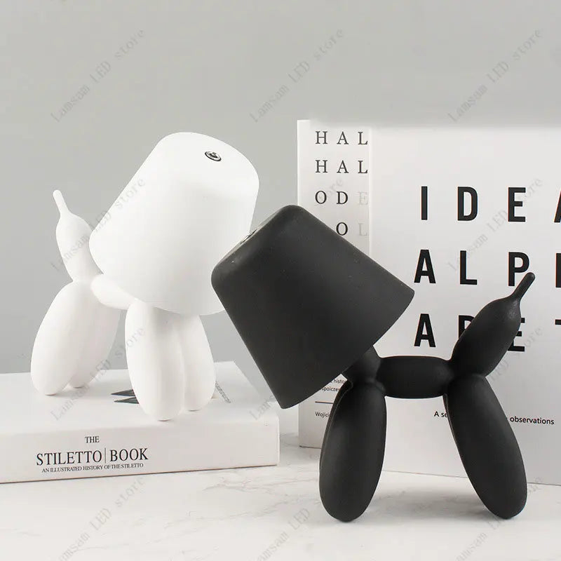 Black and white dog-shaped objects on a light gray surface with books in the background.