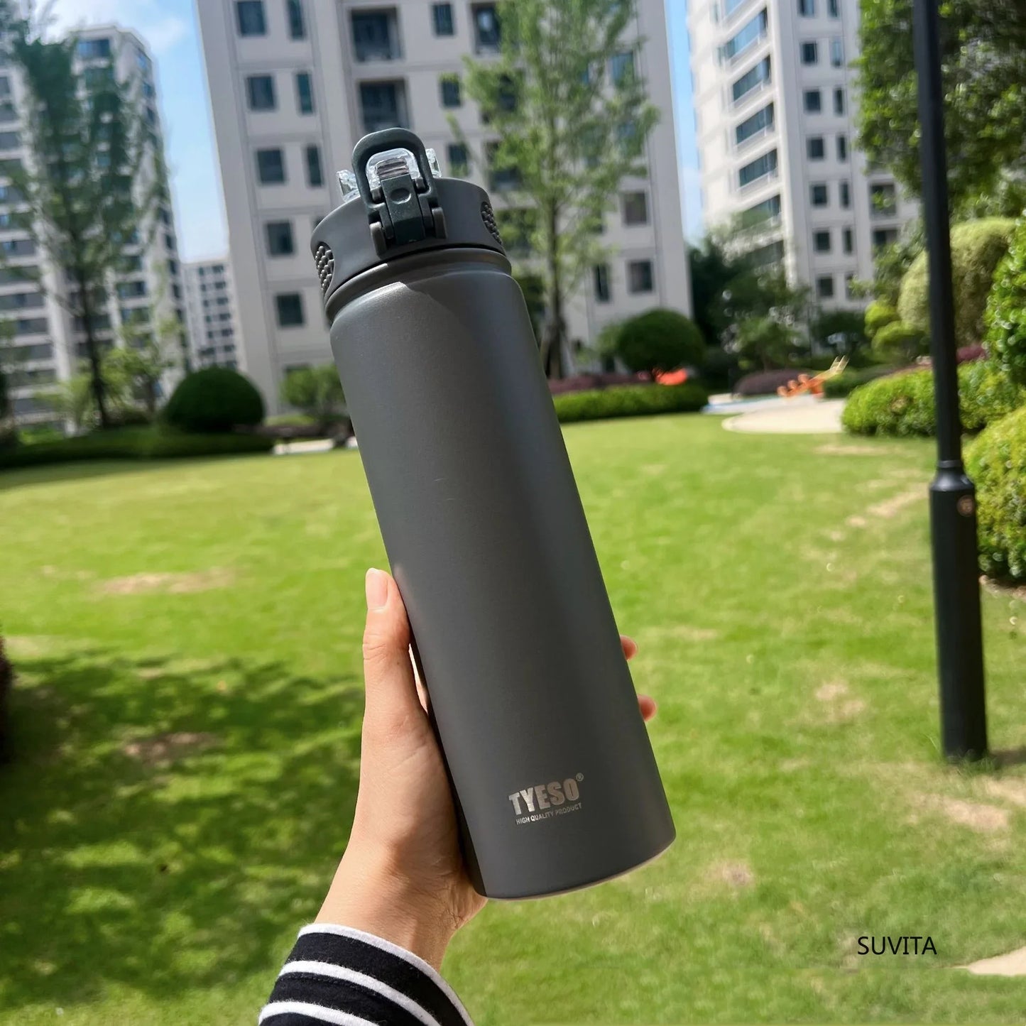 TYESO gray thermos bottle with straw held outdoors. Durable, BPA-free, and insulated for hot or cold beverages.