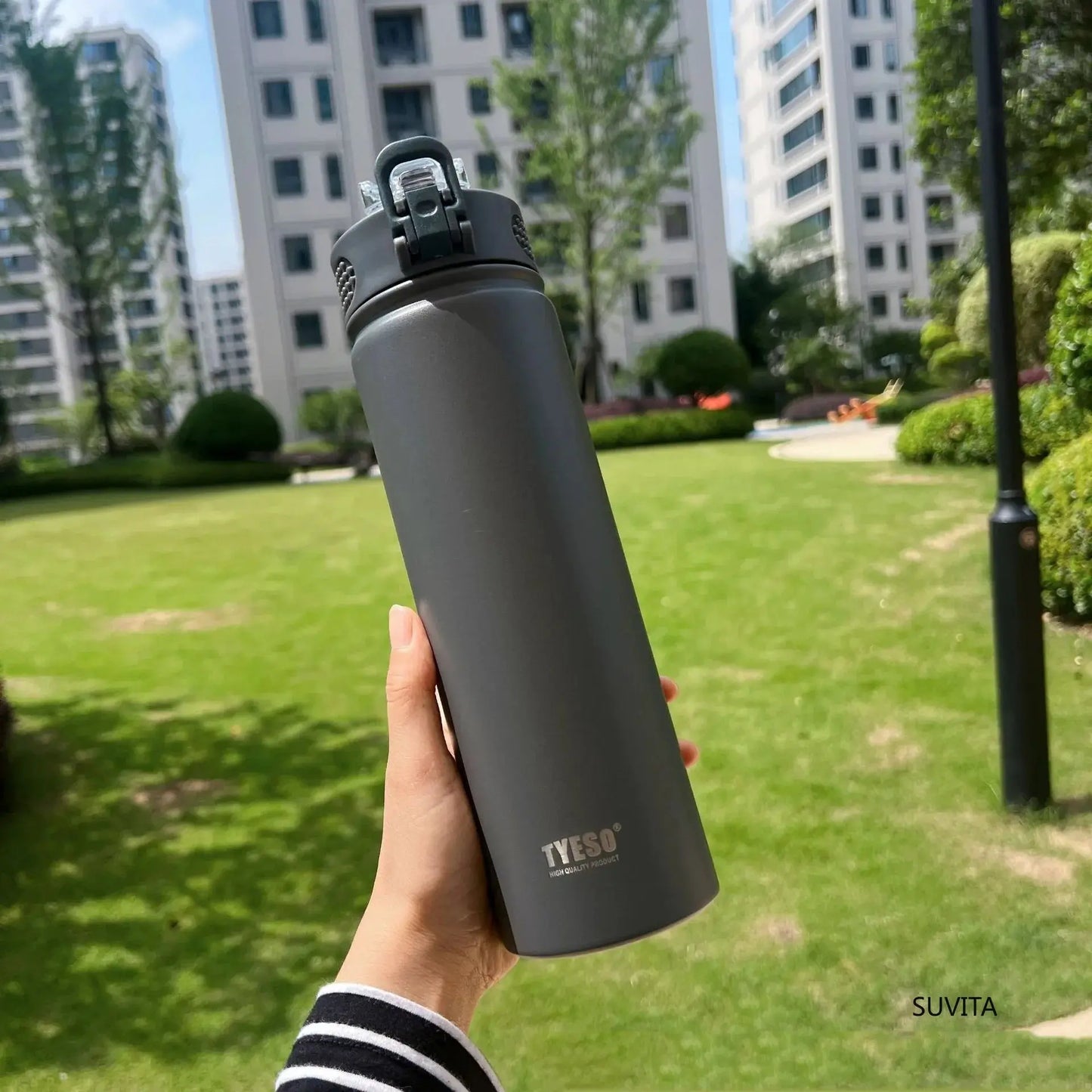 TYESO gray thermos bottle with straw held outdoors. Durable, BPA-free, and insulated for hot or cold beverages.