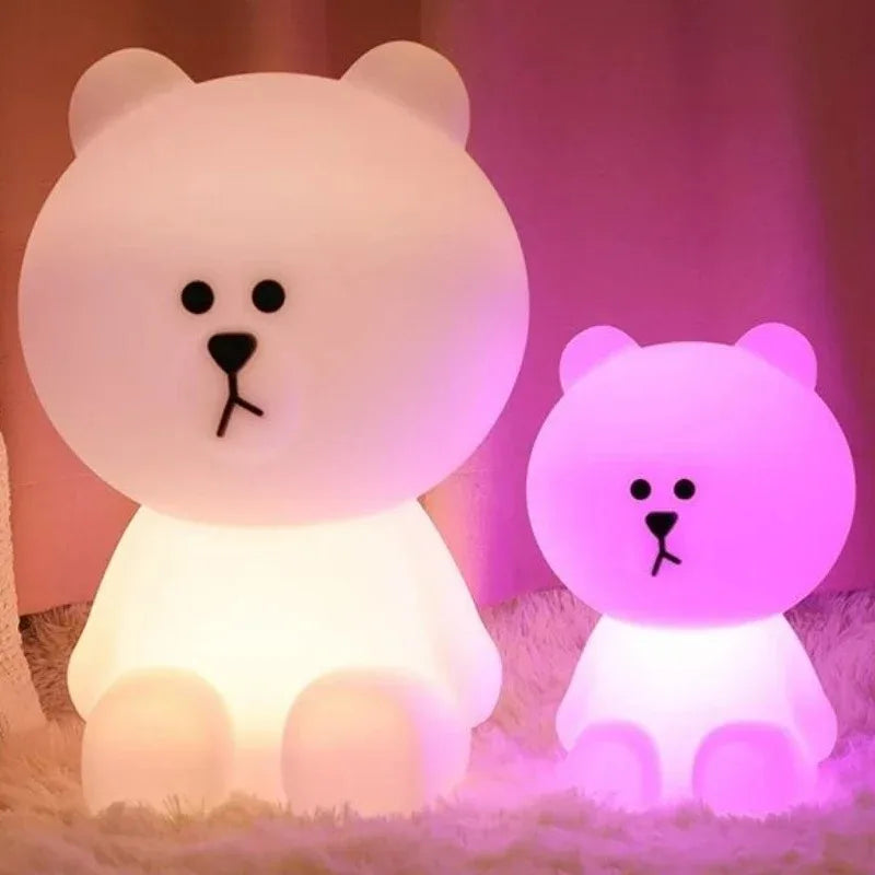 Two bear-shaped lamps, one large and one small, emitting different colors on a soft surface.