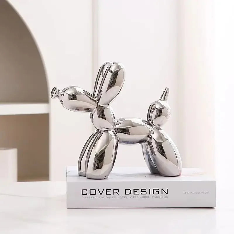 Silver balloon dog sculpture on a white surface with a neutral background