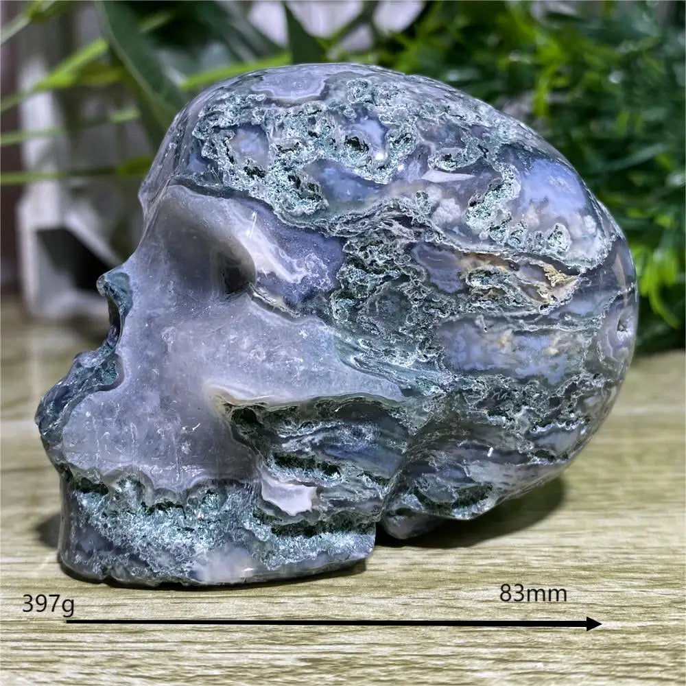 Decorative stone sculpture of a face on a wooden surface with greenery in the background