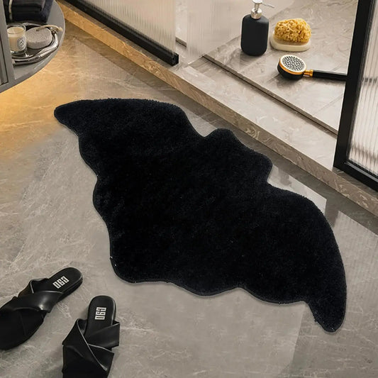 Black bath mat on a bathroom floor with slippers nearby
