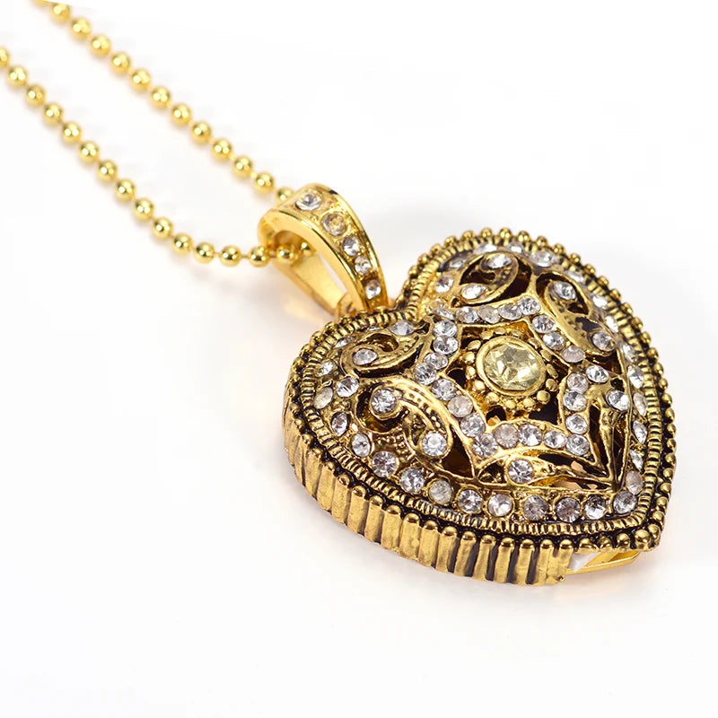 Gold heart-shaped pendant necklace with intricate designs and clear stones on a white background
