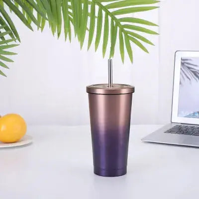 Gradient purple to rose gold tumbler with straw on a white surface with laptop and fruit.