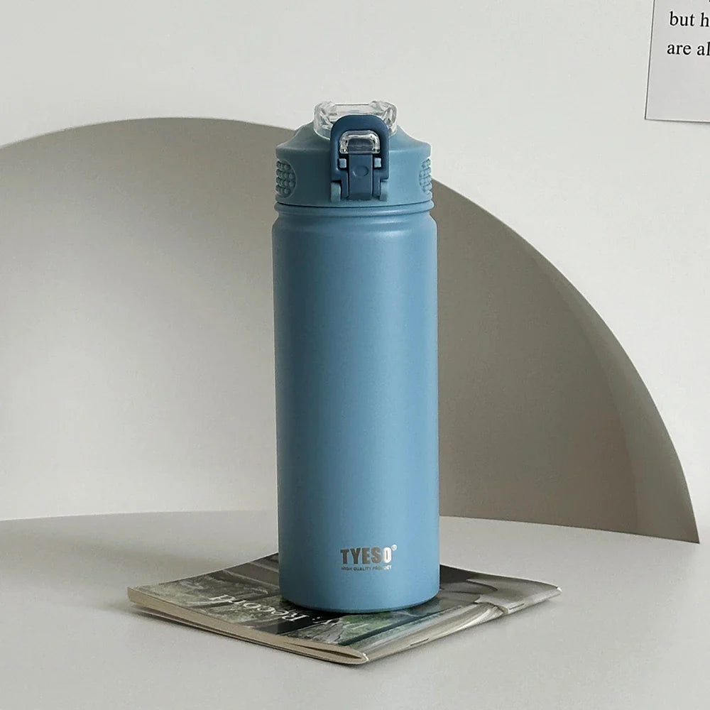 TYESO blue thermos bottle with straw on a magazine. Double-wall insulated and BPA-free for versatile use.