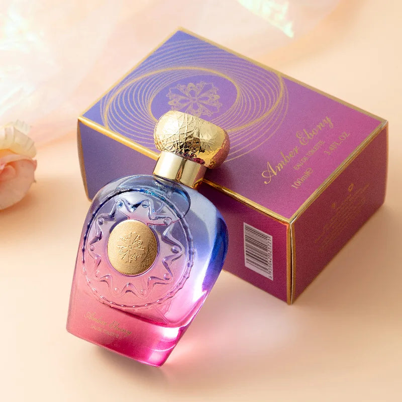 Perfume bottle with gold accents and a matching box on a soft pink background