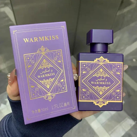 Purple 'WARMKISS' perfume bottle and packaging held by a person.