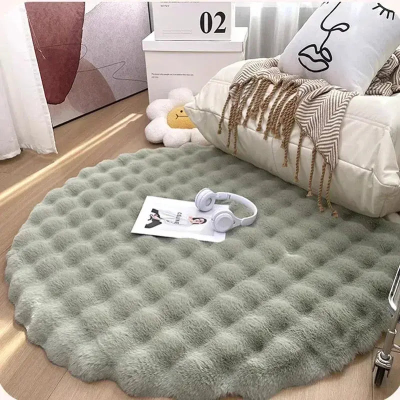 Round green rug on a wooden floor with a pillow and headphones on top