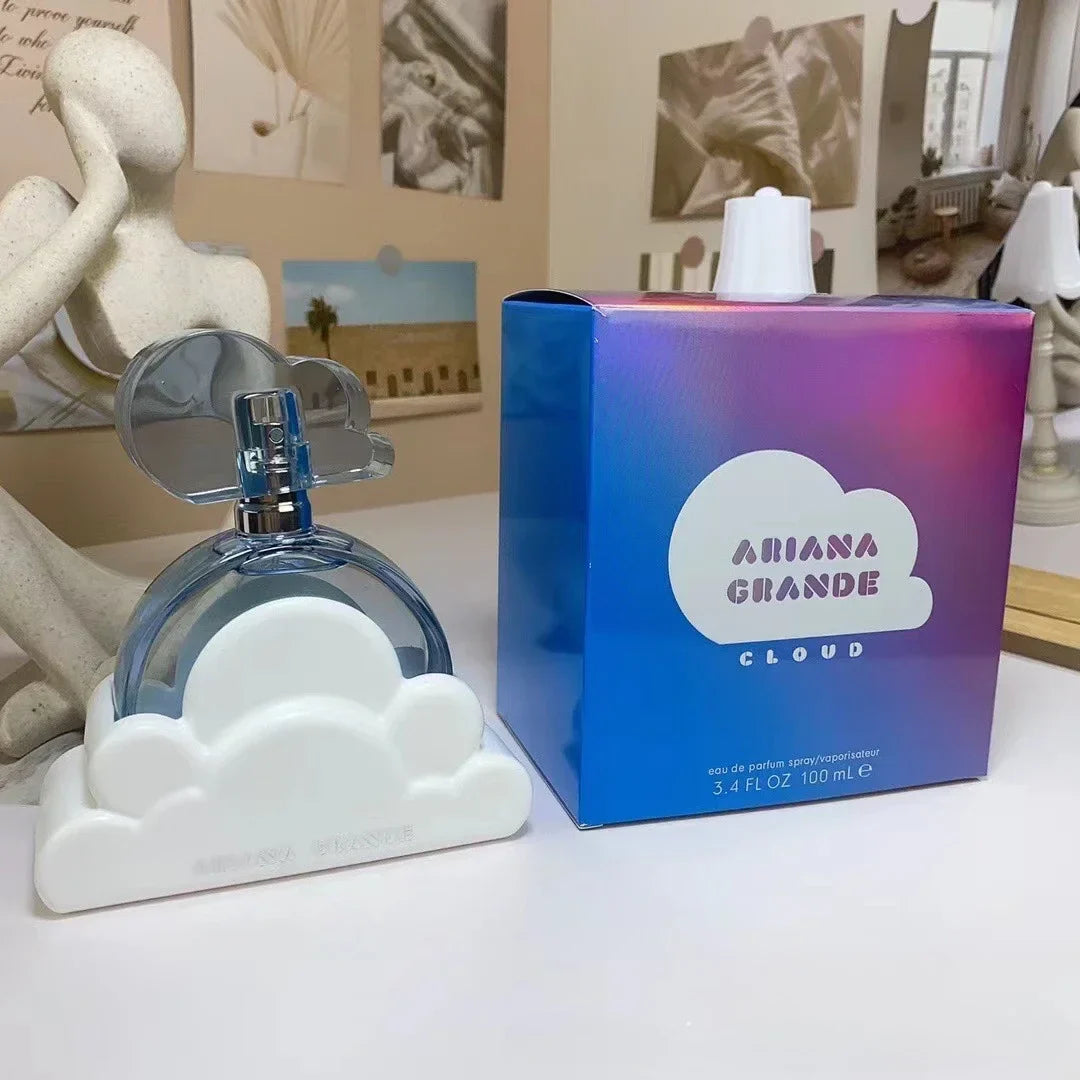Perfume bottle and packaging of 'Cloud' by Ariana Grande on a surface with decorative items in the background.