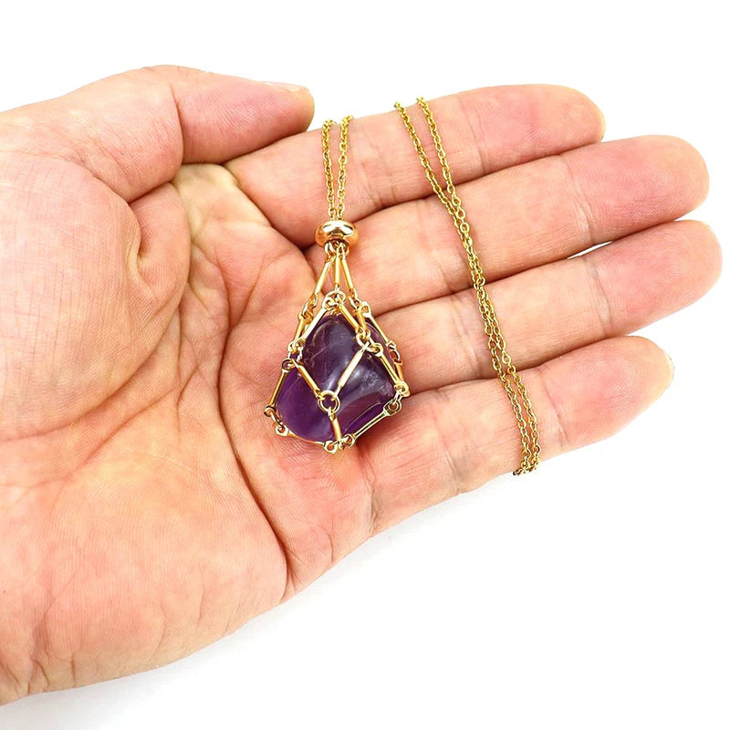 Hand holding a gold necklace with a purple gemstone pendant on a white background