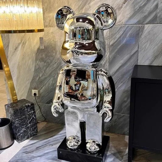 Silver robot bear sculpture in a room with marble walls and a lamp. bearbrick collectable