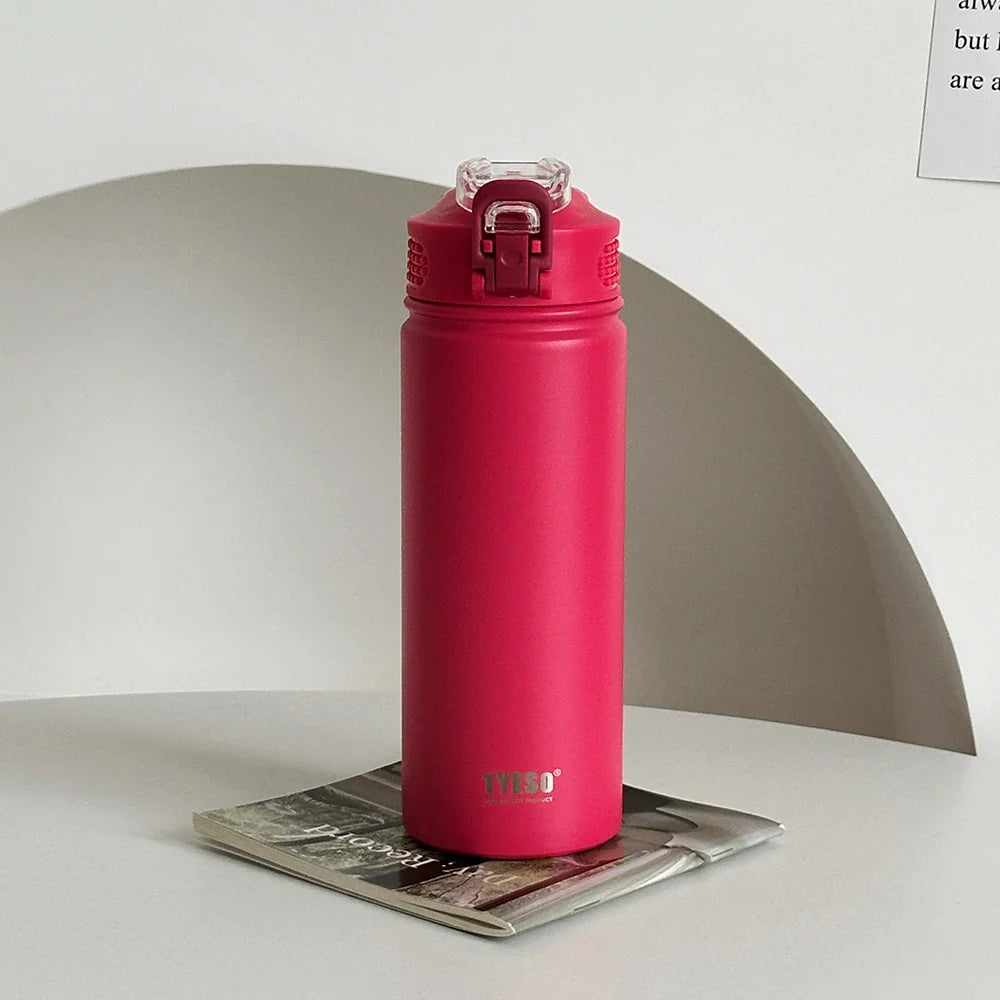 TYESO red thermos bottle with straw placed on a magazine. Leak-proof and BPA-free for stylish hydration.