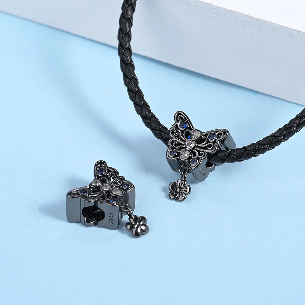 Butterfly-shaped jewelry charm on a braided cord against a light blue background pandora style charm pendant