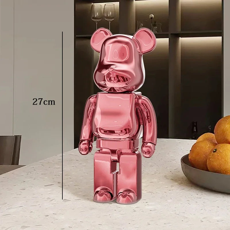 Pink bear-shaped figure on a table with a bowl of oranges in the be@rbrick collectablebackground
