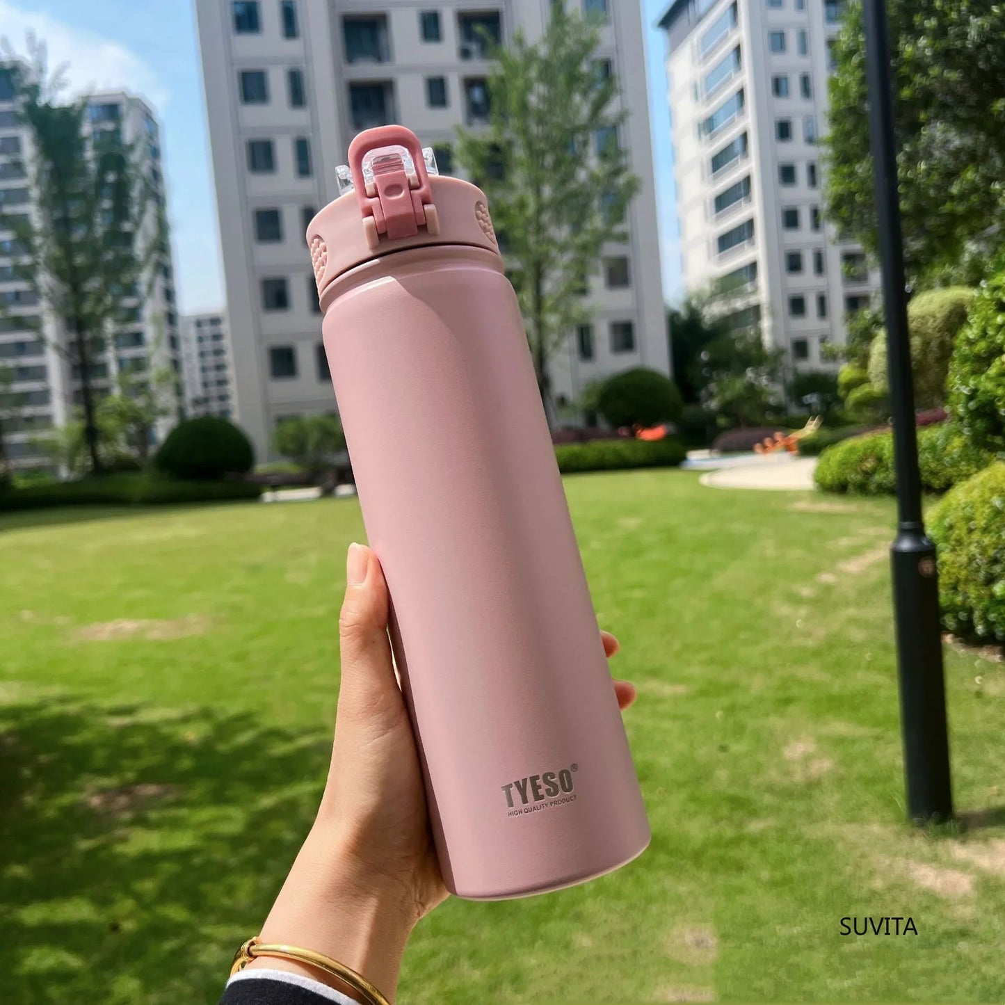 TYESO pink thermos bottle with straw held outdoors. Leak-proof and BPA-free, ideal for stylish hydration.