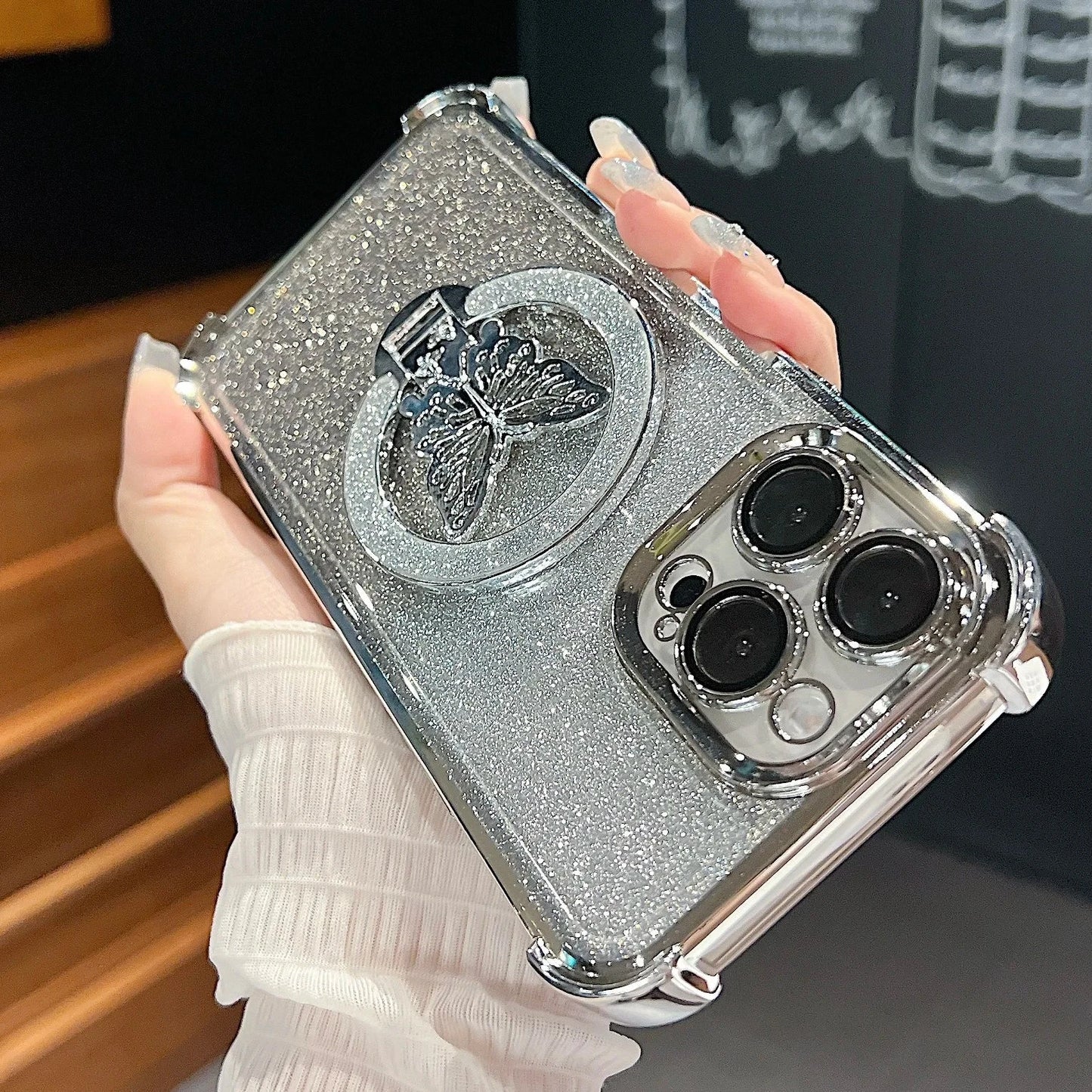 Silver glittery phone case with butterfly design held by a hand