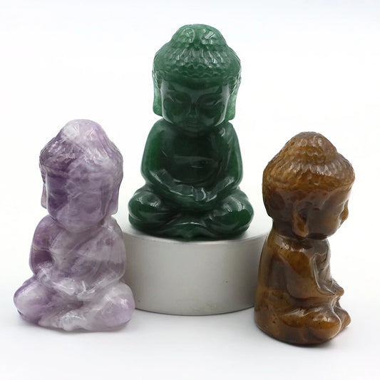 Three stone statues of Buddha in different colors on a white background