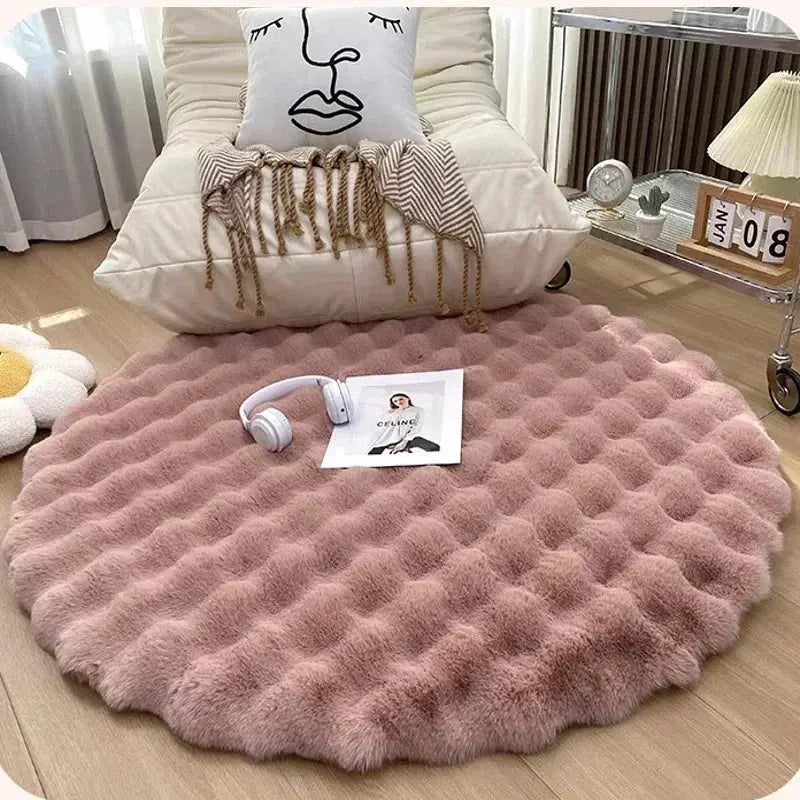 Round pink rug on a wooden floor with a pillow and headphones on top