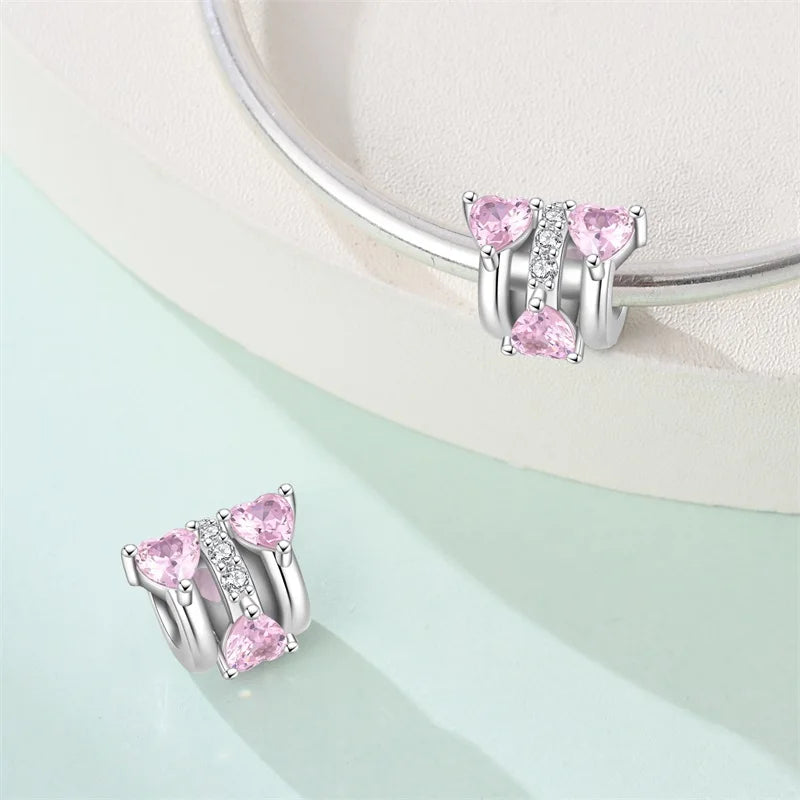 Silver earrings with pink gemstones on a light green surface. pandora style