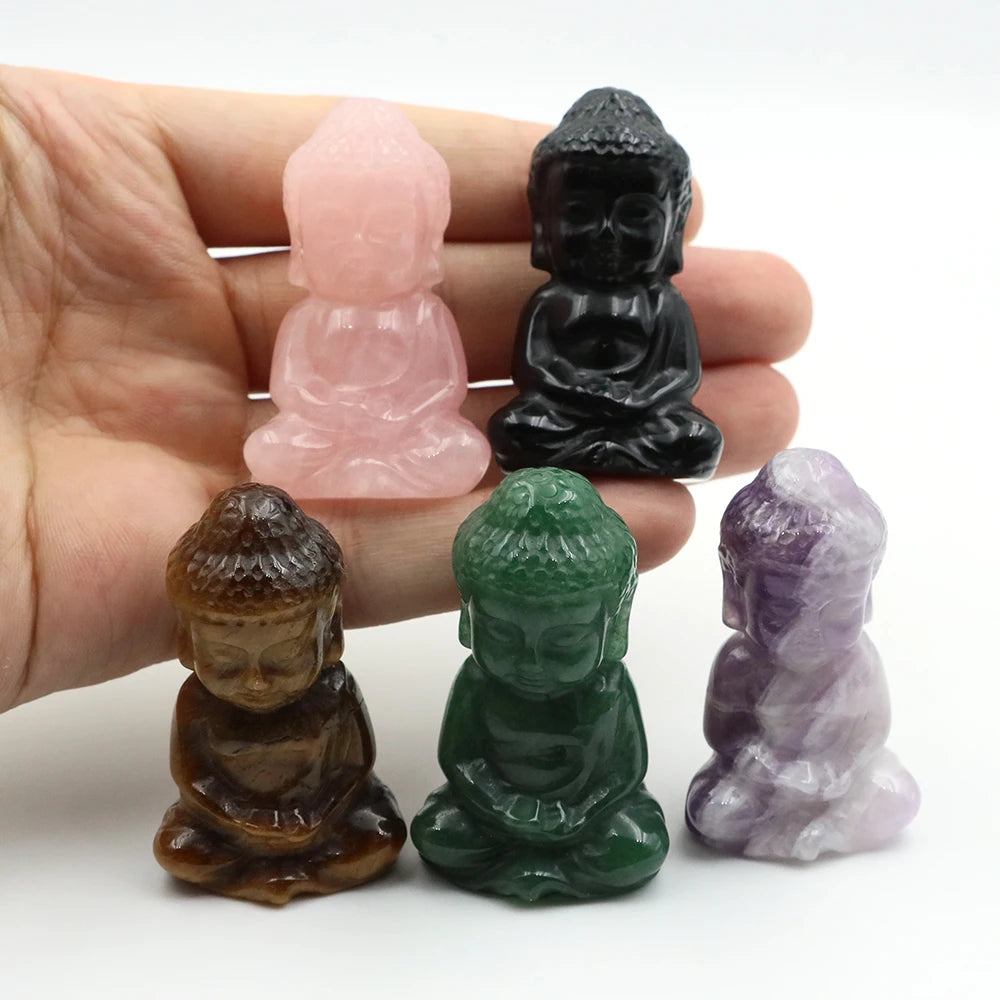 Five small stone Buddha figurines in different colors held in a hand against a white background.