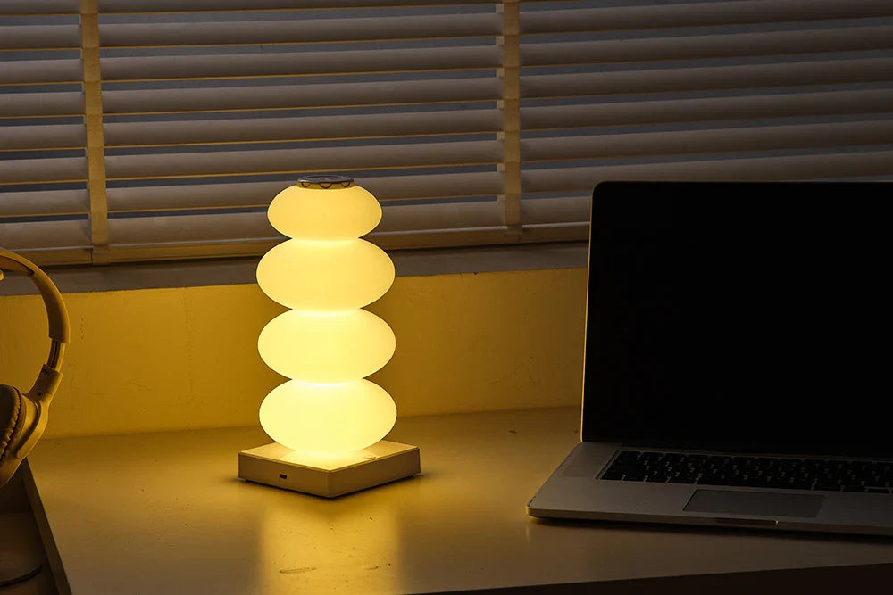 Lamp on a desk with a laptop in a dimly lit room