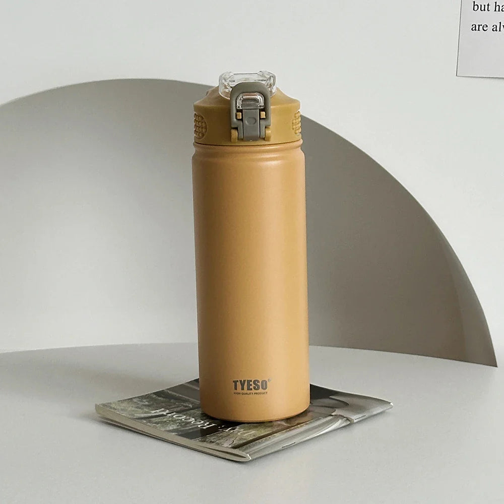 TYESO yellow thermos bottle with straw on a magazine. Leak-proof and BPA-free, ideal for travel or office.