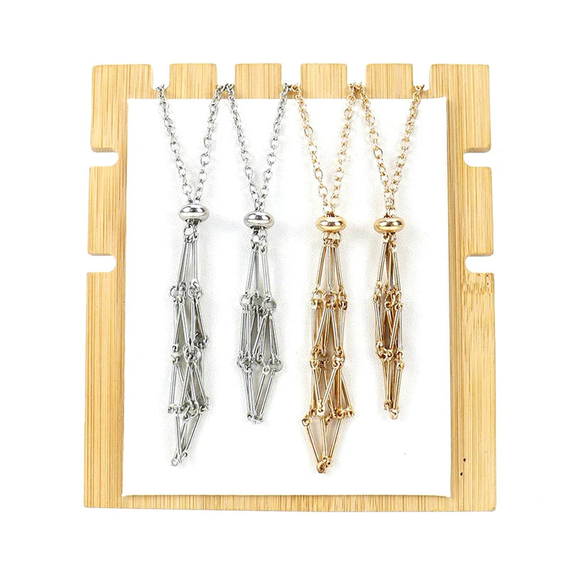 Three necklaces in silver, gold, and rose gold on a wooden stand.