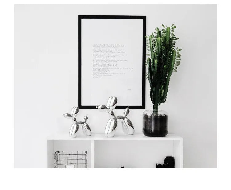 Decorative items including a framed poster, metallic dog sculpture, and potted plant on a white surface.