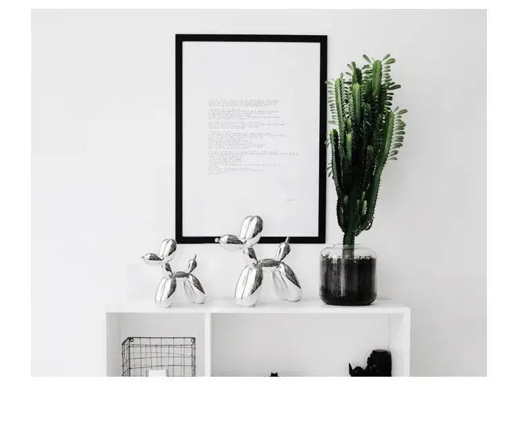 Decorative items including a framed poster, metallic dog sculpture, and potted plant on a white surface.