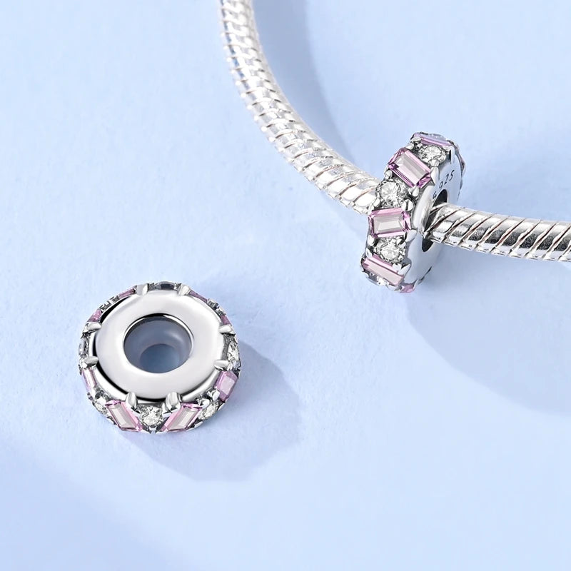 Close-up of a silver and pink beaded charm on a light blue background. pandora style