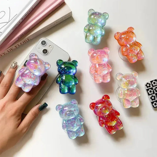 Colorful gummy bear-shaped phone cases on a white surface with a hand holding a phone.