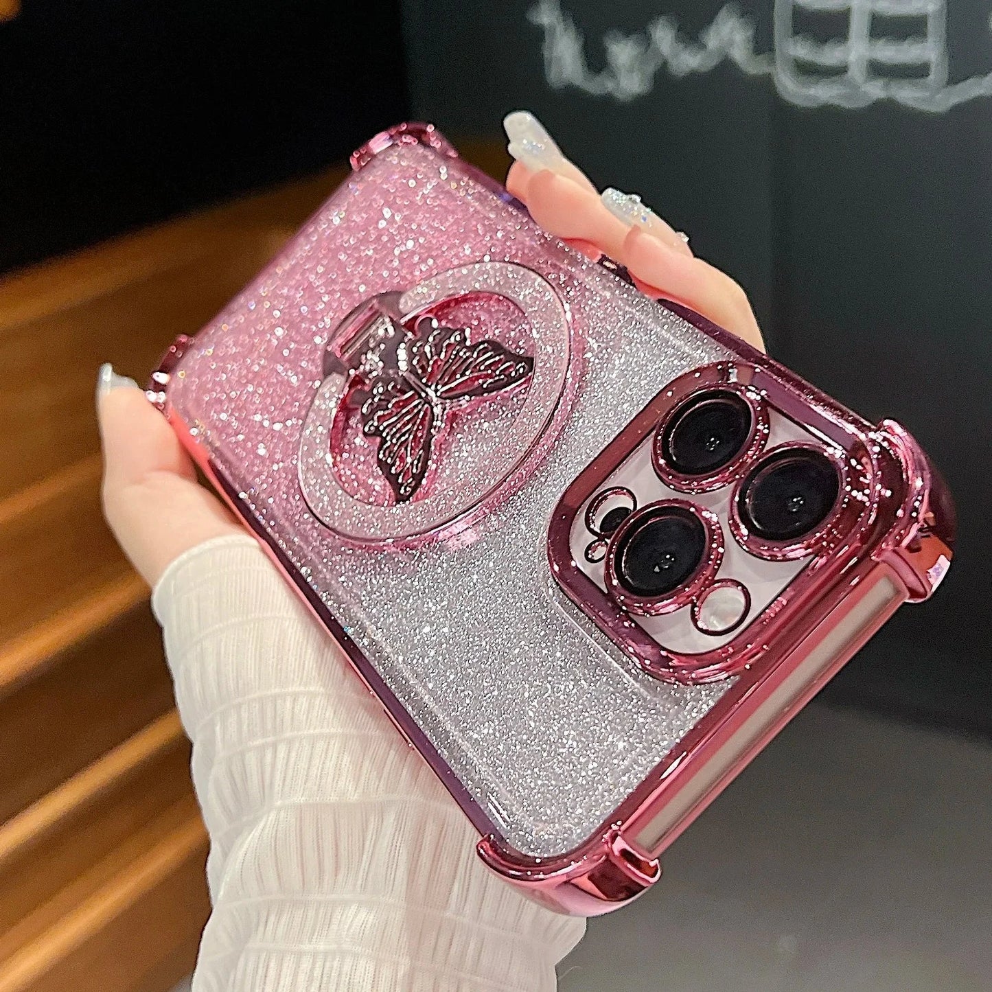 Pink glittery phone case with butterfly design held by a hand