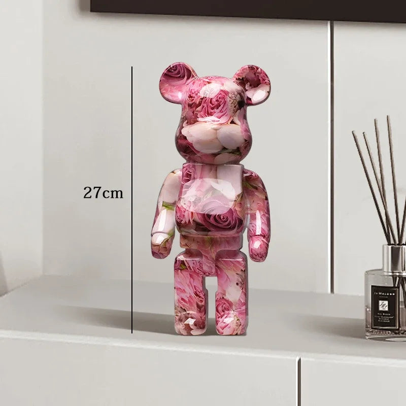 Pink floral-patterned bear figure on a white surface with a diffuser in the background be@rbrick collectable