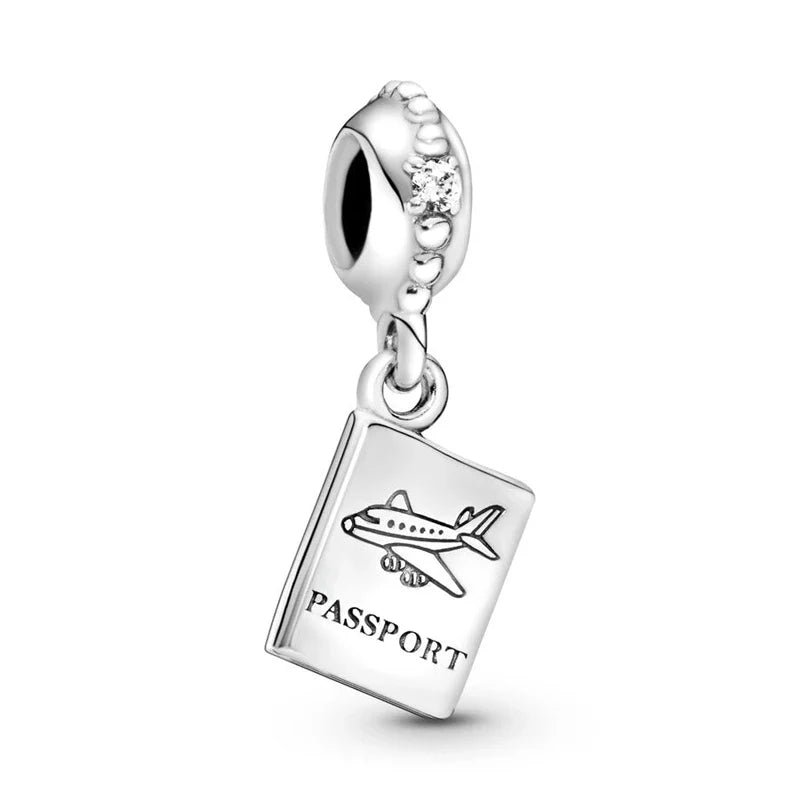 Silver charm shaped like a passport with an airplane and 'PASSPORT' text on a white background