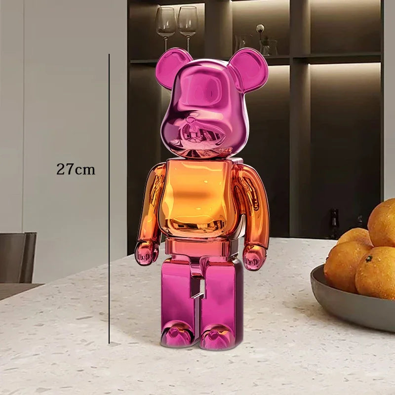 Multicolored bear-shaped figure on a table with a bowl of oranges in the background be@rbrick collectable