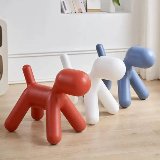 Three colorful dog-shaped stools on a wooden floor with a white wall in the background.