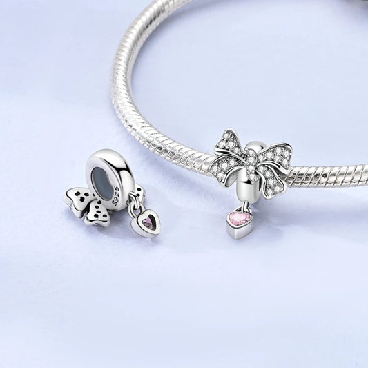 Silver bracelet with butterfly-shaped charms on a light purple background. pandora style