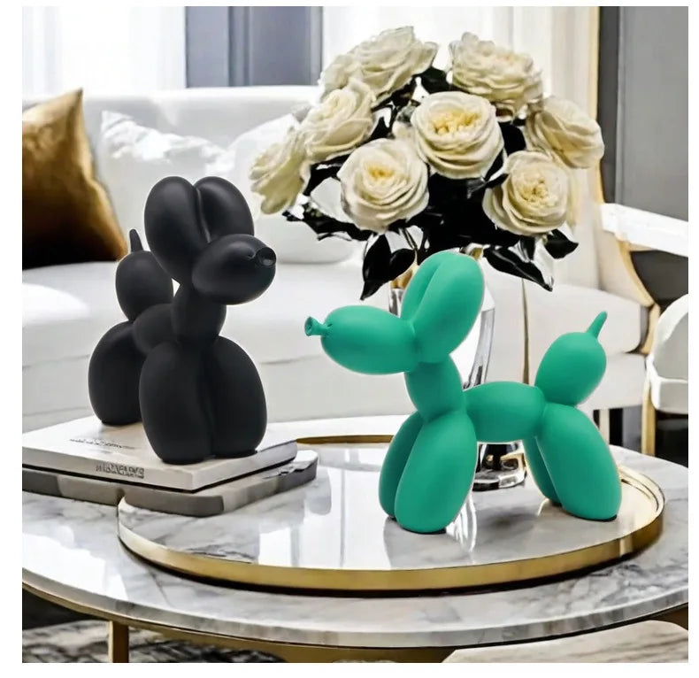 Black and green balloon dog sculptures on a table with white roses in the background.