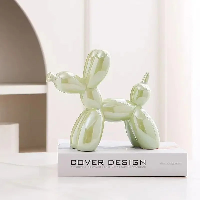 Green balloon dog sculpture on a white surface with 'Cover Design' book in the background