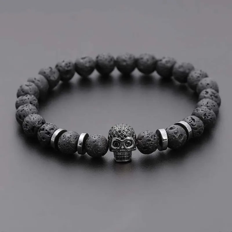 Bracelet with dark stone beads and a skull charm on a gray background