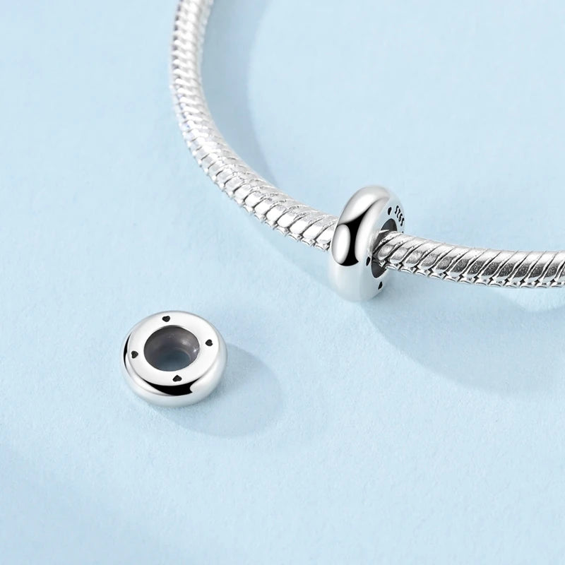 Silver charm with a black stone on a light blue background