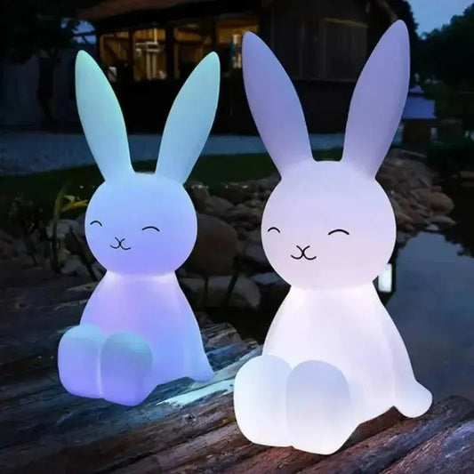 Two rabbit-shaped LED lights on a wooden surface outdoors.
