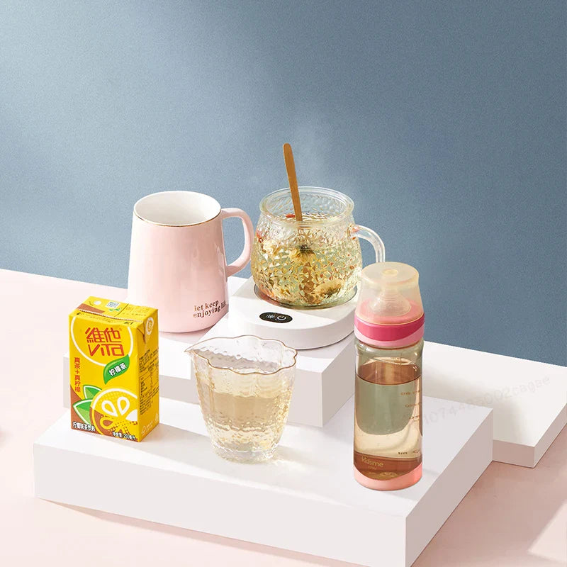 Thermostatic coffee warmer displayed with various drink containers, highlighting versatility for tea, milk, and baby bottles.