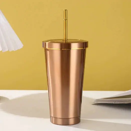 Rose gold tumbler with a straw on a yellow background